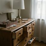 Intérieur sobre d’un appartement français après un cambriolage, avec un écrin à bijoux ouvert sur une commode et quelques objets déplacés, sans personne.